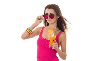 aantrekkelijk jong meisje in roze overhemd en zonnebril drinken oranje cocktail geïsoleerd Aan wit achtergrond foto