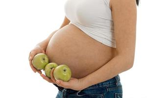 studio portret van zwanger vrouw met groen appels in haar handen geïsoleerd Aan wit achtergrond foto