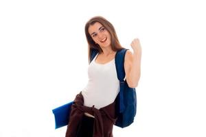 aantrekkelijk jong brunette leerling met blauw rugzak Aan haar schouders poseren geïsoleerd Aan wit achtergrond foto