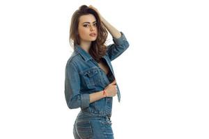 sexy jong meisje in jeans pak staat zijwaarts en poseren voor de camera foto