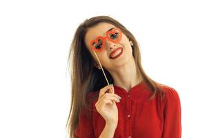 een pret vastpinnen meisje in een rood blouse lacht en houdt in de buurt oog papier bril detailopname foto