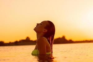 seksueel jong dame in de zee Bij warm zonsondergang foto