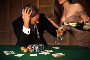 foto emotioneel Mens verliezer in poker en Dames giet hem een glas van Champagne