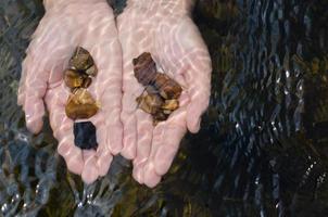 stenen in handen onder Doorzichtig water foto