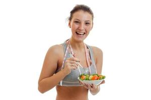 gelukkig jong sport- vrouw eet salade en lachend foto