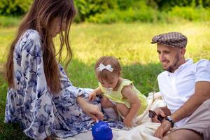 portret van gelukkig familie hebben pret Bij de park. ouders met dochter ontspannende buitenshuis. foto