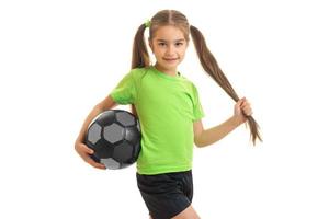 mooi weinig meisje in groen overhemd met voetbal bal in handen foto