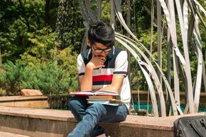 jong leerling zit Aan een bank en leest boeken foto