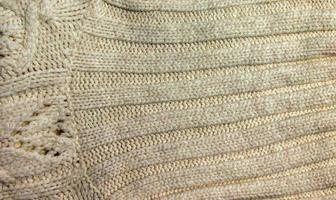 de structuur van een groot breien trui of sjaal. gebreid achtergrond met een Verlichting patroon. wol hand- of machine breien. kleding stof achtergrond. foto