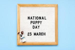 voelde bord met tekst nationaal puppy dag in 23 maart, schattig hond figuren Aan blauw achtergrond top visie vlak leggen vakantie groet kaart foto