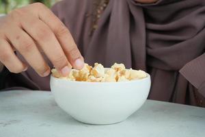 hand- plukken een smakelijk popcorn zittend buitenshuis foto