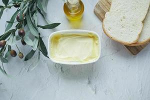 vers olijf- boter in een houder met brood Aan wit achtergrond foto