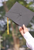 leerling houden hoeden in hand- gedurende aanvang succes Aan geel achtergrond foto