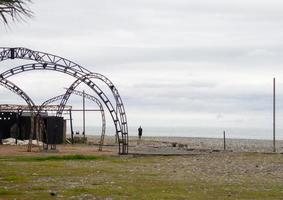 een Mens Aan de kust De volgende naar een verlaten structuur. kader van roestig stukken van ijzer Aan de kust. foto