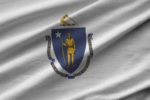 Massachusetts ons staat vlag met groot vouwen golvend dichtbij omhoog onder de studio licht binnenshuis. de officieel symbolen en kleuren in banier foto