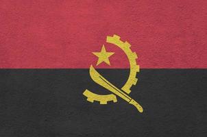 Angola vlag afgebeeld in helder verf kleuren Aan oud Verlichting bepleistering muur. getextureerde banier Aan ruw achtergrond foto