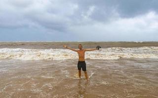 Mens is uit Aan strand gedurende orkaan en geniet Mexico. foto