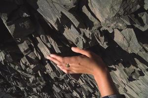 dichtbij omhoog vrouw hand- aanraken basalt rots concept foto