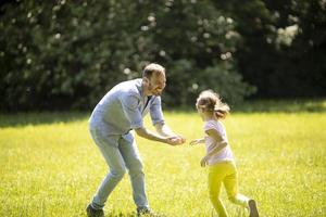 vader die zijn dochtertje achtervolgt tijdens het spelen in het park foto