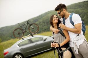 glimlachen jong paar wandelen met rugzakken Aan de groen heuvels foto