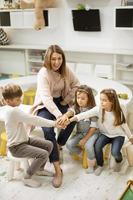 schattig peuter- kinderen zetten handen samen met hun kinderkamer leraar foto