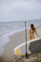 jong vrouw met peddelen bord Aan de strand Aan een zomer dag foto