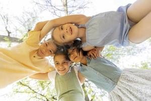 groep van Aziatisch en Kaukasisch gelukkig kinderen ineengedoken, op zoek naar beneden Bij camera en glimlachen foto