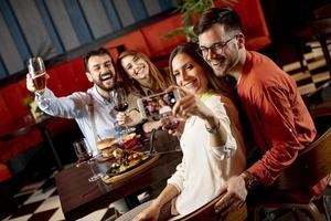 knap jong vrienden maken selfie en glimlachen terwijl hebben een avondeten in restaurant foto