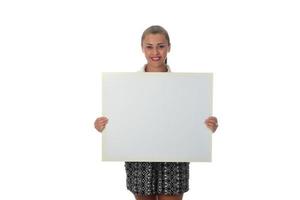 jong glimlachen vrouw Holding een blanco vel van papier voor reclame foto