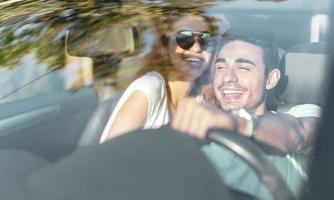 vrienden hebben pret Bij auto reis in de omgeving van de wereld. paar in liefde met armen omhoog Aan een converteerbaar auto. foto