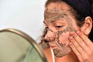 mooi vrouw Verwijderen klei gelaats masker van haar gezicht foto