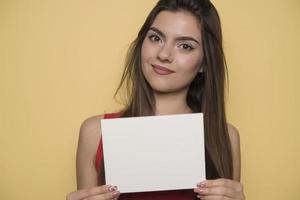 jong glimlachen vrouw Holding een blanco vel van papier voor reclame foto