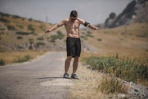 atletisch jong Mens uitrekken na rennen in de natuur. sport concept foto