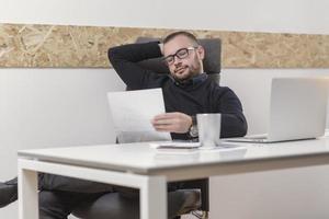 jonge zakenman die thuis werkt met laptop en papieren op bureau foto