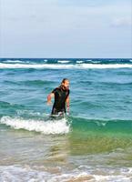 mannetje komt eraan uit van de oceaan na water surfing foto