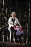 grootmoeder en haar autistisch groots dochter genieten van vakantie samen buitenshuis, aan het liegen Aan groen gras Aan deken en glimlachen naar camera. vrije tijd familie levensstijl, geluk en momenten. foto