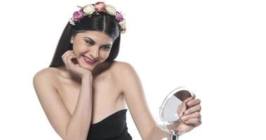 mooi aantrekkelijk brunette vrouw controle haar gezicht huid in voorkant van een spiegel Aan wit achtergrond. foto