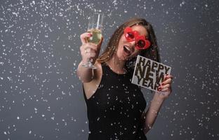 mooi vrouw vieren nieuw jaar met confetti en Champagne Holding teken. geïsoleerd foto