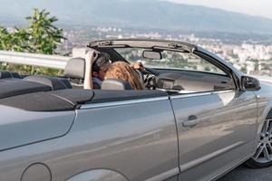 vrienden hebben pret Bij auto reis in de omgeving van de wereld. paar in liefde met armen omhoog Aan een converteerbaar auto. foto