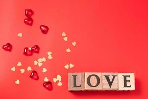 kubussen met tekst liefde, met harten en confetti Aan rood achtergrond. Valentijnsdag dag. ansichtkaart, groet kaart ontwerp. liefde, viering concept. vrij ruimte voor tekst, kopiëren ruimte. foto