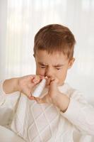 weinig jongen sproeien geneeskunde in neus, neus- druppels. kleuter kind gebruik makend van nasaal spuiten. vloeibaar neus, koud, griep, ziekte, virus. dichtbij omhoog. foto