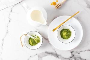 matcha thee poeder in wit keramisch kommen en een speciaal bamboe meten lepel Aan een marmeren tafel. top visie. traditioneel Japans thee. foto