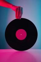 hand- houden retro vinyl schijf met neon lichten. wijnoogst muziek- achtergrond foto