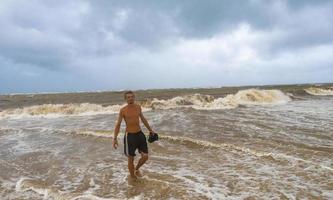 Mens is uit Aan strand gedurende orkaan en geniet Mexico. foto