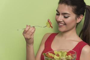 portret van een gelukkig speels meisje aan het eten vers salade van een kom foto