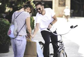 portret van vrolijk Kaukasisch jong paar Mens en vrouw Holding veel papier Tassen na boodschappen doen terwijl wandelen en pratend Aan straat. gelukkig familie paar met pakketjes buitenshuis. buying concept foto