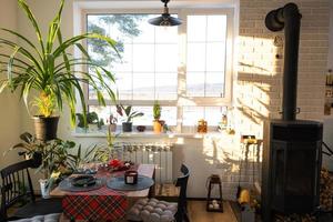 zonnig interieur van een loft-stijl huis met ingemaakt planten, een groot venster, een gedekt tafel voor de Kerstmis en nieuw jaar vakantie foto