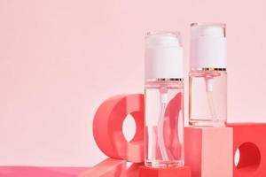 twee glas flessen met verstuiven en dispenser Aan een roze podium Aan een roze achtergrond, flessen voor parfum of serum foto