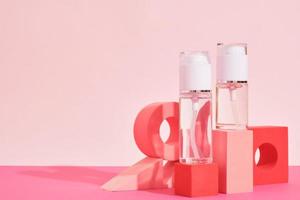 twee glas flessen met verstuiven en dispenser Aan een roze podium Aan een roze achtergrond, flessen voor parfum of serum foto