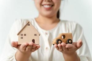 verward Aziatisch vrouw koper kiezen tussen buying nieuw huis of auto. foto